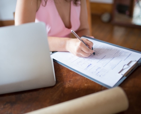 Woman filling in registration forms next to a laptop