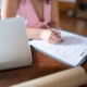 Woman filling in registration forms next to a laptop