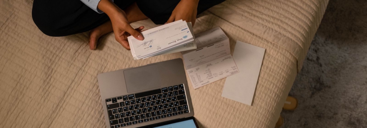 Business owner holding a cheque next to a laptop while reviewing cash flow