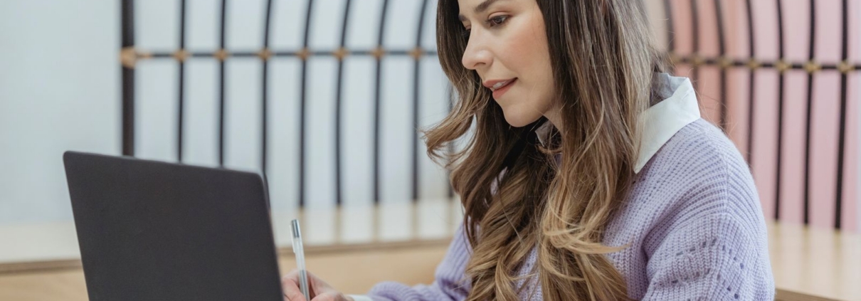 Entrepreneur writing notes at a laptop while working on a business plan
